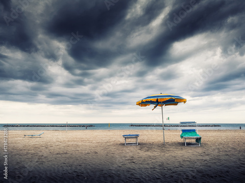 Ombrellone e sdraio solitari al mare sotto cielo tempestoso photo