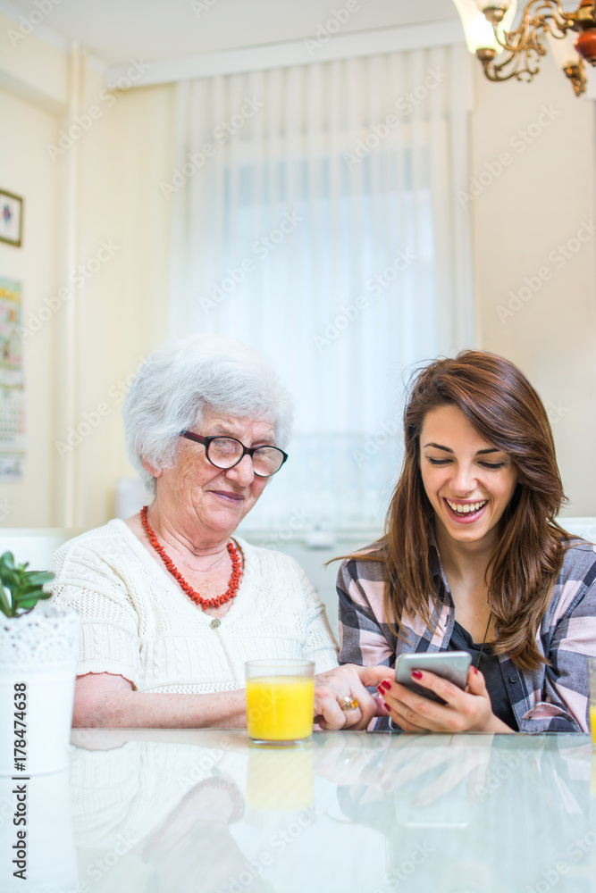 Granddaughter showing something on phone to her grandmother.