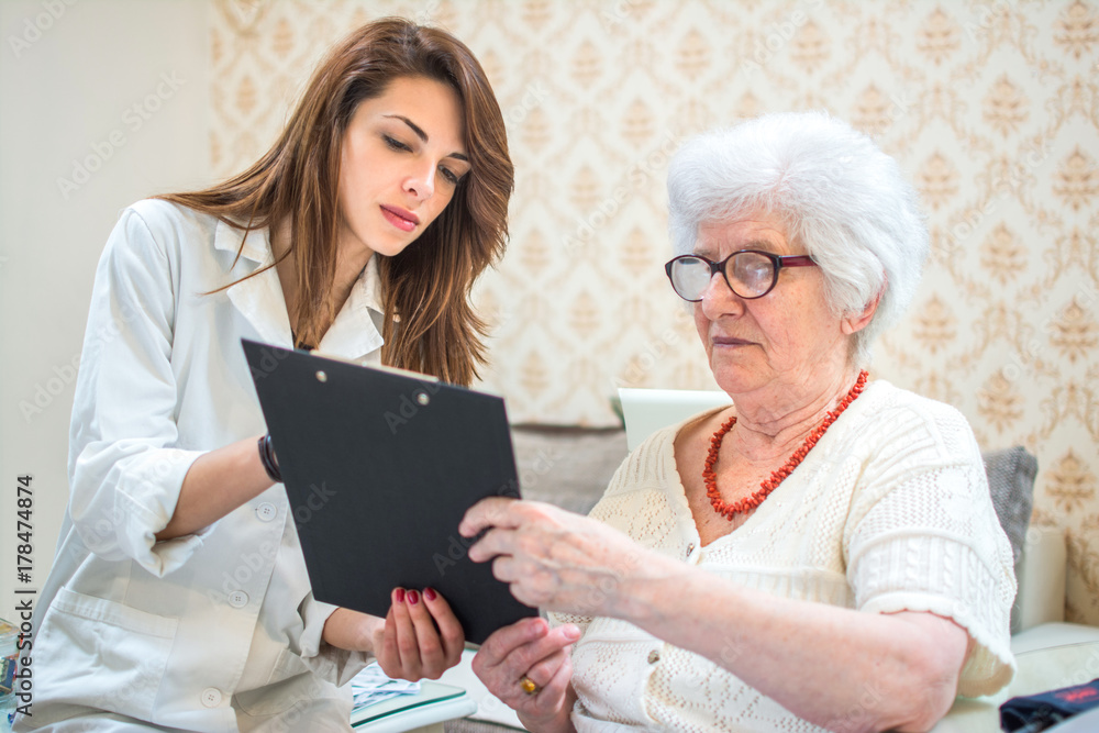 Young female doctor showing reports to senior patient. Home care. Young female doctor showing reports to senior patient. Home care.