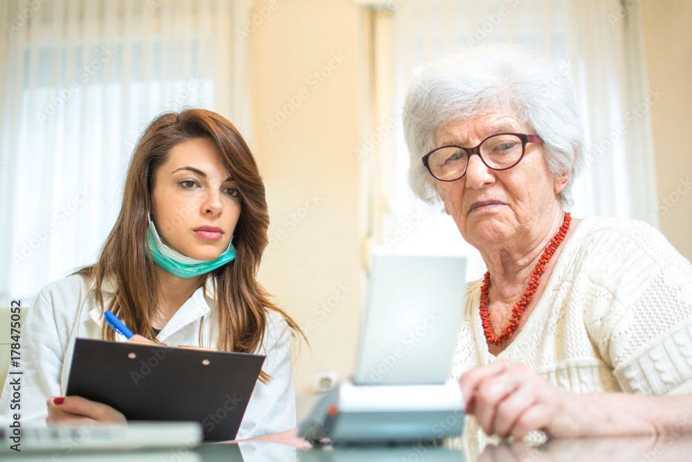 Nurse with clipboard writing results of blood pressure measurement of female senior patient. Nurse with clipboard writing results of blood pressure measurement of female senior patient.