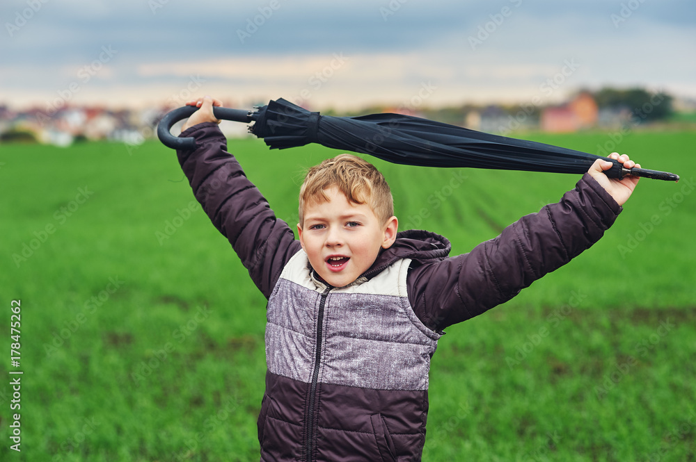 boy walking with umbrella in autumn in a field boy walking with umbrella in autumn in a field