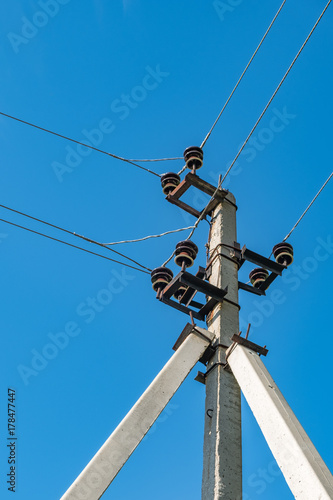 Triple support concrete electric pole against the sky