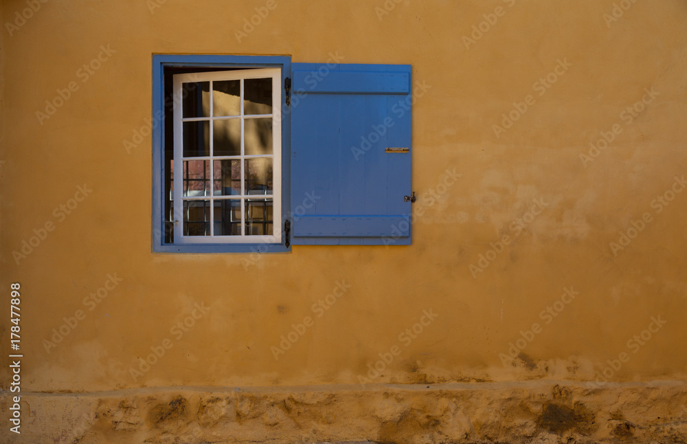 Rustic blue shutter and window with yellow ochre background
