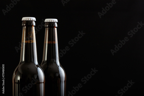 Closeup of two beer bottles isolated on black background