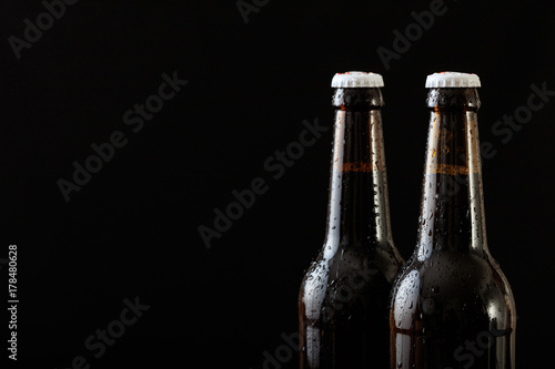 Closeup of two beer bottles isolated on black background