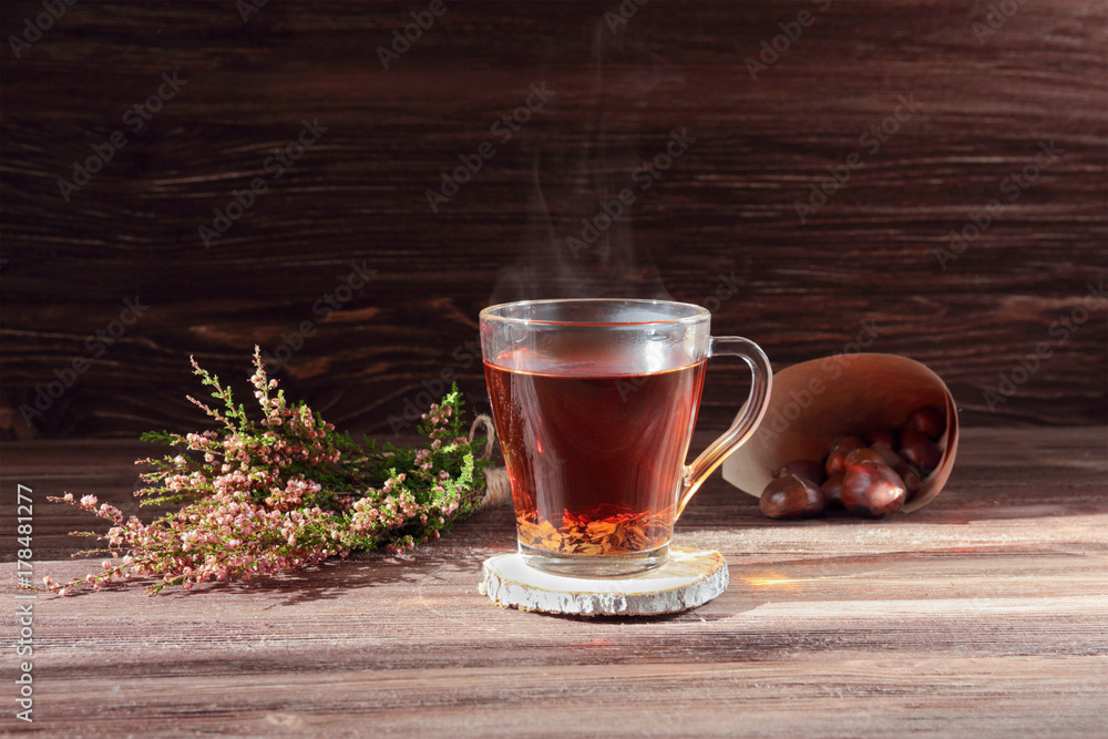 still life with a cup of tea, a bag of chestnuts and heather on a dark wooden background still life with a cup of tea, a bag of chestnuts and heather on a dark wooden background