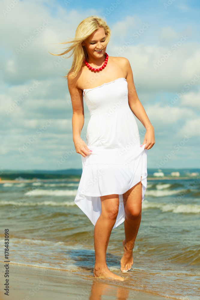 Blonde woman wearing dress walking in water Blonde woman wearing dress walking in water