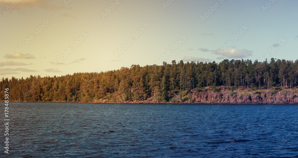 The view of the rocky coast of the mountain lake at sunset. View from passing boat