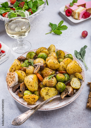 Fried potatoes with vegetables and herbs on gray stone background. Healthy food concept.