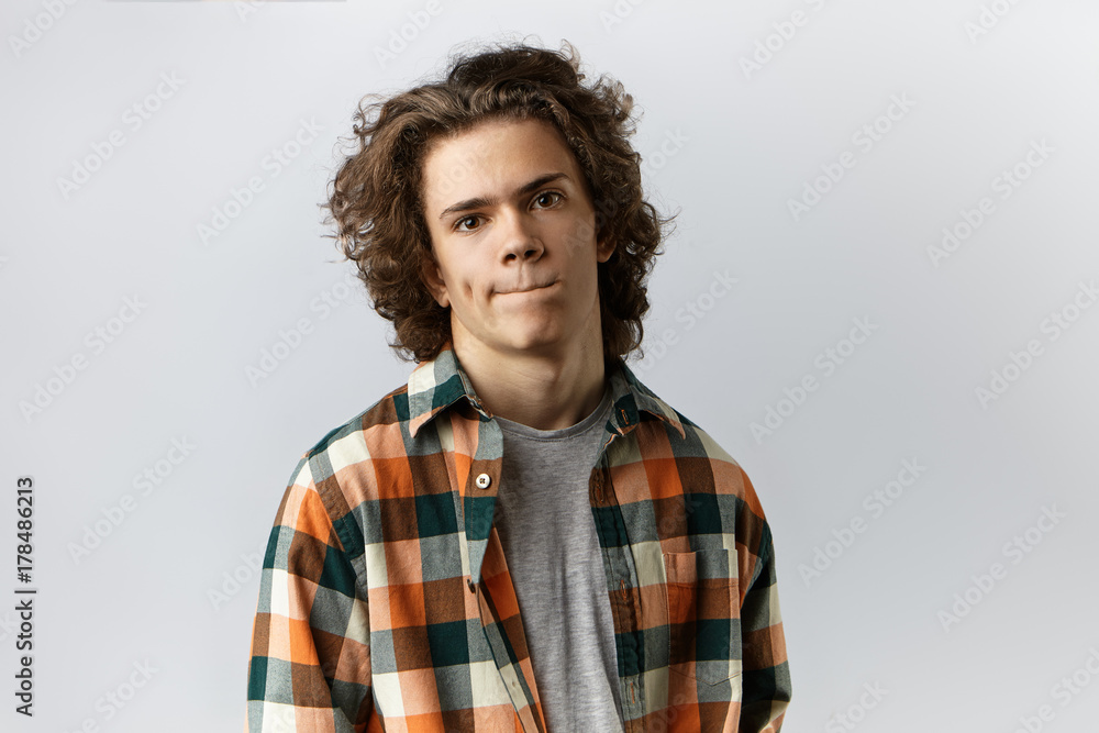 Human emotions, feelings, reaction and attitude. Isolated picture of stylish unsure young male wearing trendy checkered shirt pursing lips, feeling nervous before first date with gorgeous woman Human emotions, feelings, reaction and attitude. Isolated picture of stylish unsure young male wearing trendy checkered shirt pursing lips, feeling nervous before first date with gorgeous woman