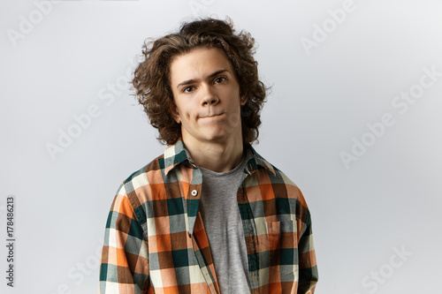 Human emotions, feelings, reaction and attitude. Isolated picture of stylish unsure young male wearing trendy checkered shirt pursing lips, feeling nervous before first date with gorgeous woman