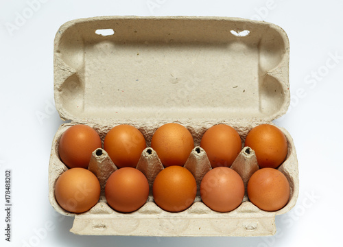 Raw chicken eggs in egg box on white background.
