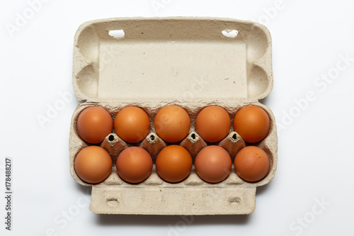 Raw chicken eggs in egg box on white background.