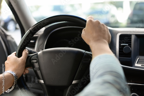 Male hands on steering wheel of a car