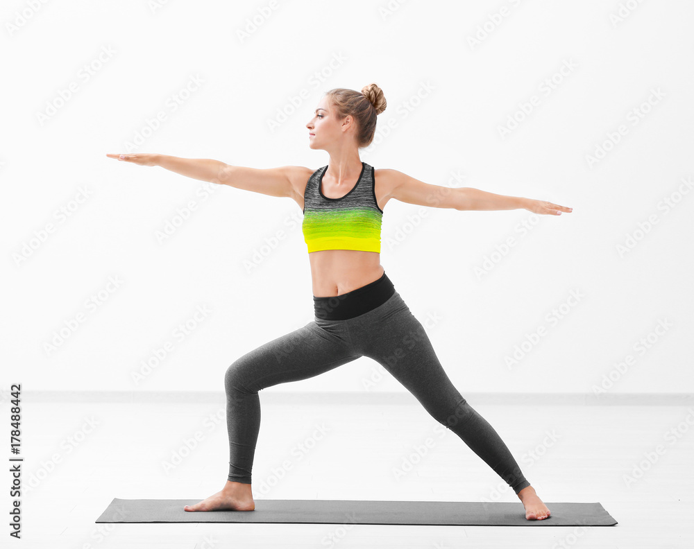 Beautiful young woman practicing yoga indoors