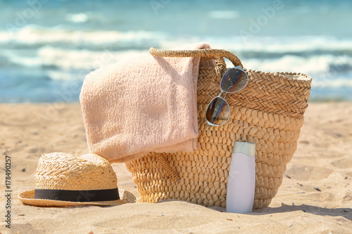 Bag with beach towel and summer accessories on sand