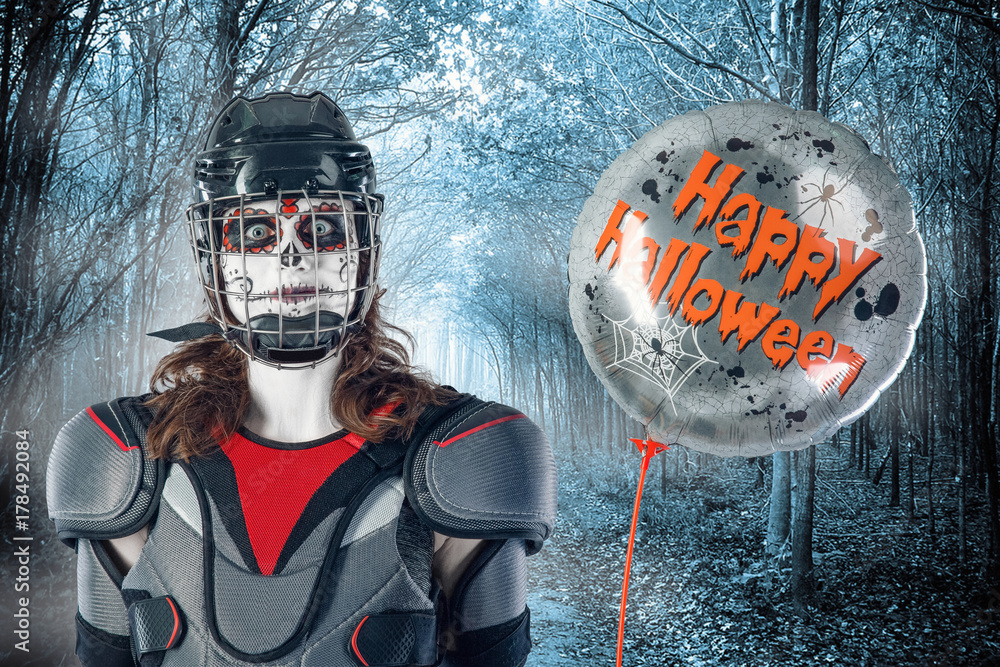 Happy halloween. hockey player in a hockey helmet and mask with a balloon  against the backdrop or background of scary forest. All Saints' Day Stock  Photo | Adobe Stock