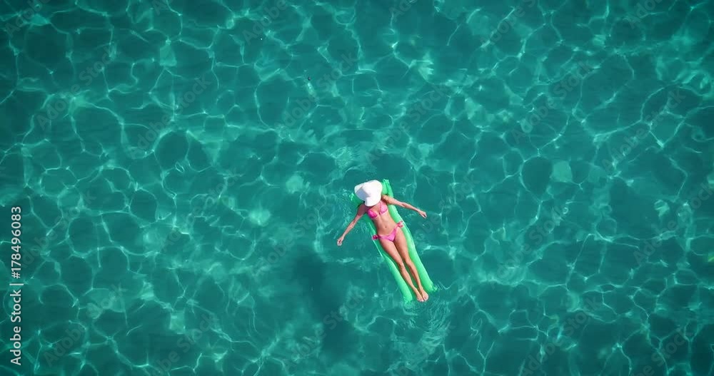 A beautiful young girl is lying on a mattress in the open sea or in the ...