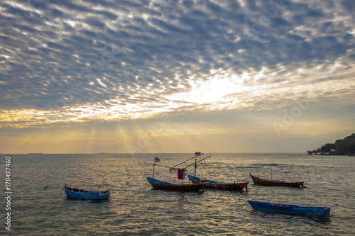 domestic fishery boat on plain sea and dramatic of cloud and sun light sky