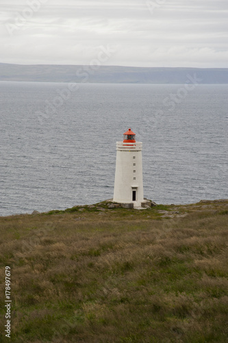 Lighthouse in a typical Icelandic landscape Vatnsnes Peninsula, a wild nature of rocks and shrubs, rivers and lakes.