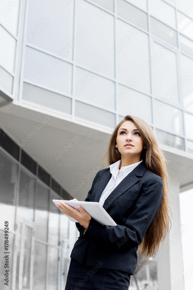 Successful businesswoman or entrepreneur using a digital tablet computer, standing in front of his office. Successful businesswoman or entrepreneur using a digital tablet computer, standing in front of his office.