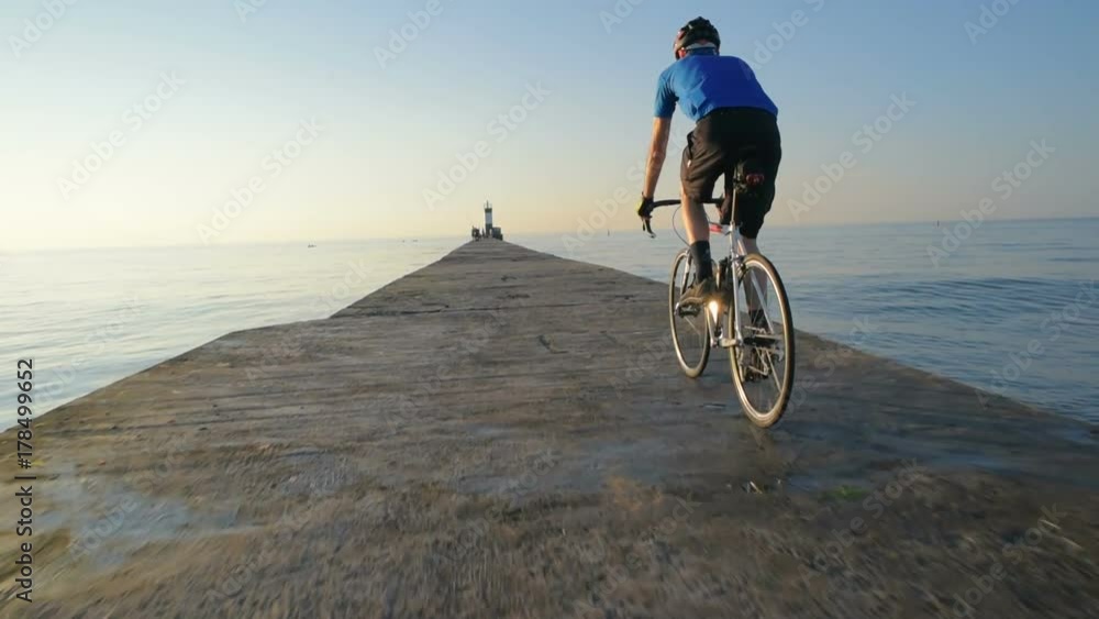 man riding bicycle on pier near the sea port man riding bicycle on pier near the sea port