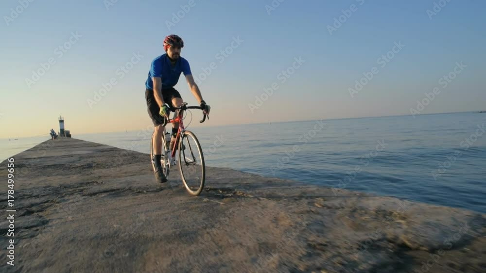 man riding bicycle on pier near the sea port man riding bicycle on pier near the sea port