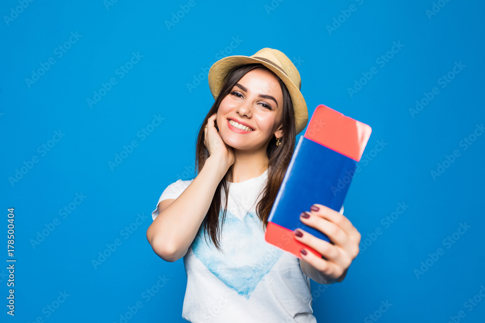 Portrait of a cheerful cute girl traveller in summer clothes showing passport with tickets to camera isolated over blue background Portrait of a cheerful cute girl traveller in summer clothes showing passport with tickets to camera isolated over blue background