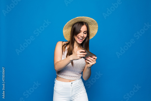 Photos Woman play game on her cell phone isolated over blue background