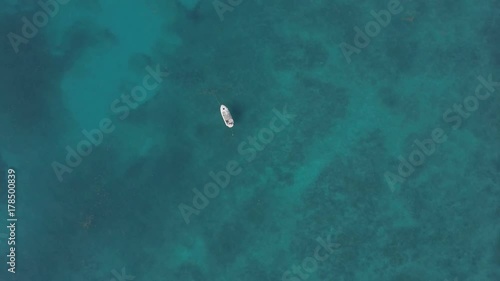 Drone looking straight down at a boat anchored in the middle of the Atlantic Ocean off the Florida Keys. The water is calm but enough to create an texture in the clear turquoise Caribbean sea. The sea