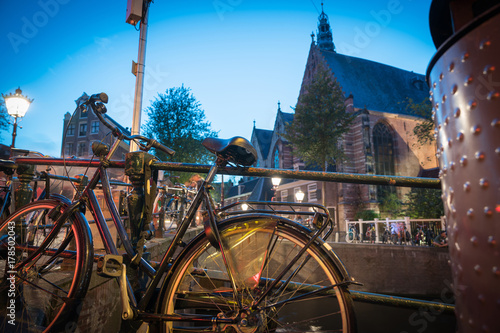 Bicycle padlocked to railing with defocused background lights on street in long exposure night scene