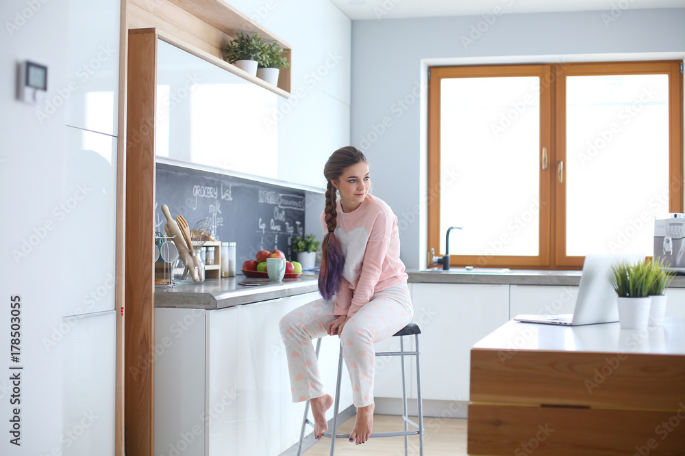 Young woman sitting on table in the kitchen. Young woman sitting on table in the kitchen.