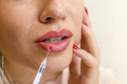 Closeup beauty shot  woman applying botox injection in lower lip    hyaluronic collagen concept 