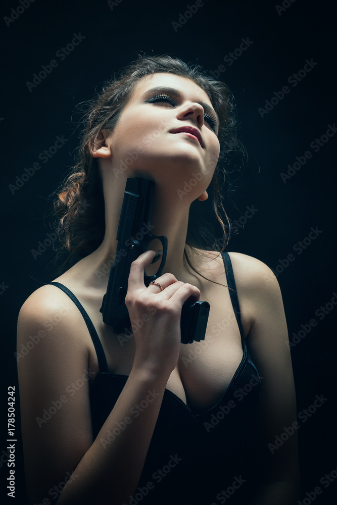 Fototapeta premium sensual beautiful woman with gun on black background
