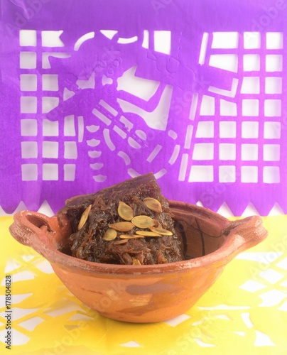 Mexican traditional pumpkin sweet made with piloncillo and cinammon on a clay pot, known as calabaza en tacha with ornamental papel picado photo