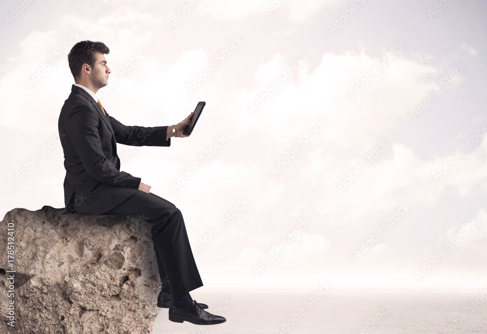 Business man sitting on stone edge Business man sitting on stone edge