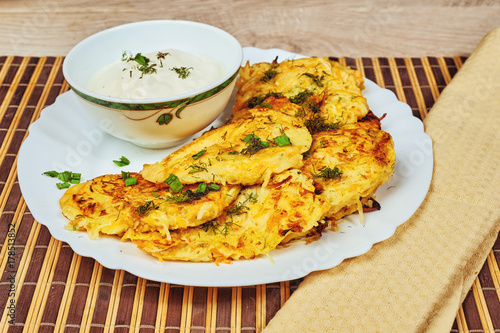 Fried potato pancakes with sour cream on old wooden background . Traditional Ukrainian cuisine