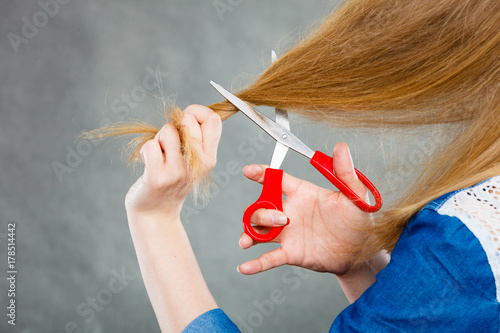 Blonde woman cutting her hair. photo