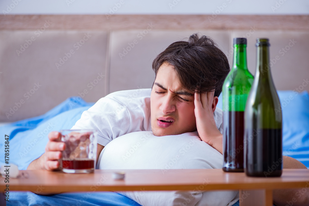 Man alcoholic drinking in bed going through break up depression Man alcoholic drinking in bed going through break up depression
