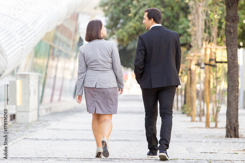 Back View of Two Partners Walking on Street photo