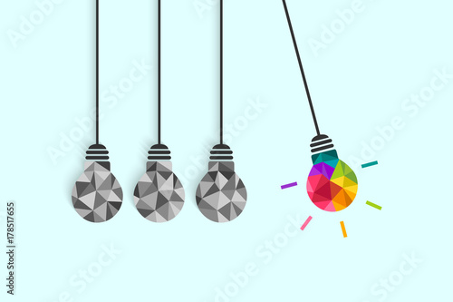 Newton's cradle pendulum with hanging light bulbs as idea and creativity concept. Colorful bulb among plain grey ones.