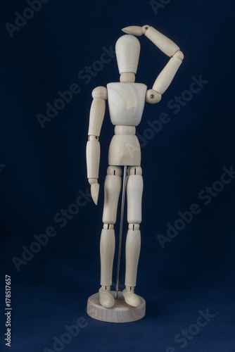 a wooden dummy posing standing	with a blue background	