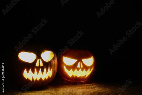 Scary Halloween pumpkins on a black background. Scary glowing pumpkins faces.