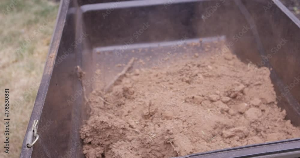 Dirt being dropped into wheel barrow - close up slow motion Dirt being dropped into wheel barrow - close up slow motion