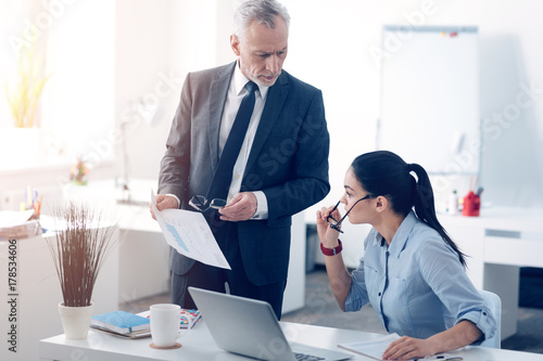 Dissatisfied chief carping at business document with his office worker