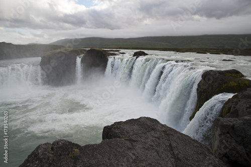 Wonderful view of Gadafoss Falls in a typical Icelandic landscape, a wild nature of rocks and shrubs, rivers and lakes.