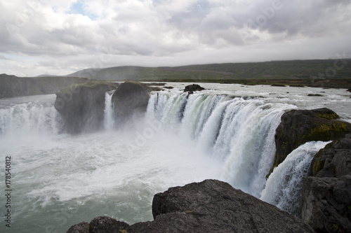 Wonderful view of Gadafoss Falls in a typical Icelandic landscape, a wild nature of rocks and shrubs, rivers and lakes.