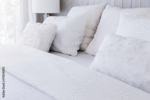 Bed maid-up with clean and cozy white pillows and bed sheets in beauty room. Close-up. Lens flair in sunlight.