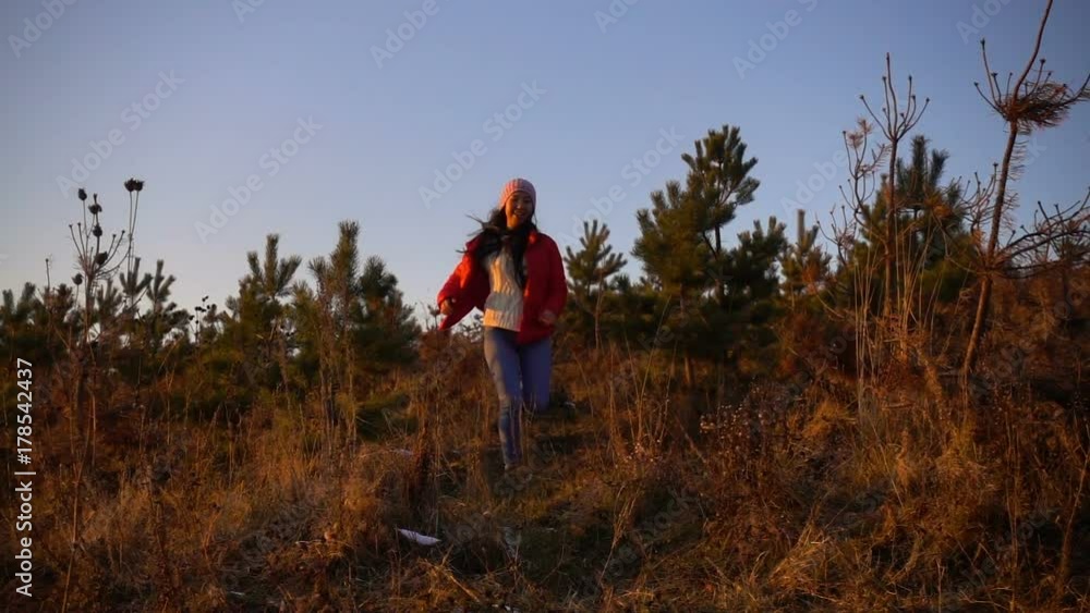 a young asian girl happily running through a mountain field of at golden sunset and jumps, slow motion, front view a young asian girl happily running through a mountain field of at golden sunset and jumps, slow motion, front view