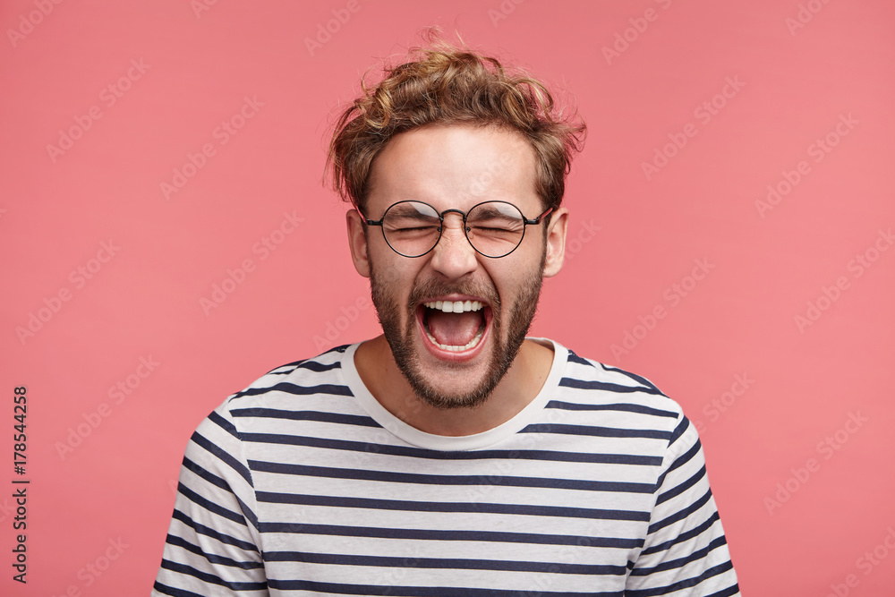 Isolated shot of overjoyed unshaven male screams in happiness, closes eyes and opens mouth, being glad to win tourist voucher, happy spend holidays abroad in exotic country, together with lover - obrazy, fototapety, plakaty 